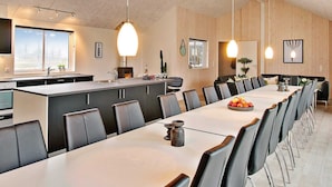 A modern kitchen with a large island, a dining area with a long table and chairs, and a view of the outdoors through a skylight. - Holiday Home in Kappeln (Kappeln)