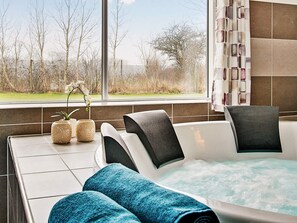 A spa area with a hot tub, seating, and a view of the outdoors.