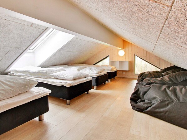 A modern attic bedroom with skylights, a skylight ceiling, and a bed with a headboard.