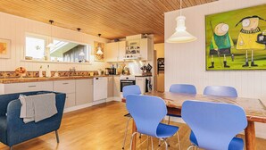 A modern kitchen with wooden ceiling, white cabinets, and blue chairs. - Deluxe Holiday Home in Løkken near Sea (Lokken)