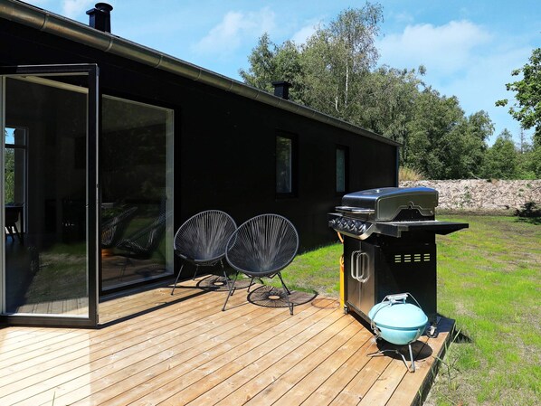 A modern outdoor deck with a grill and seating area.