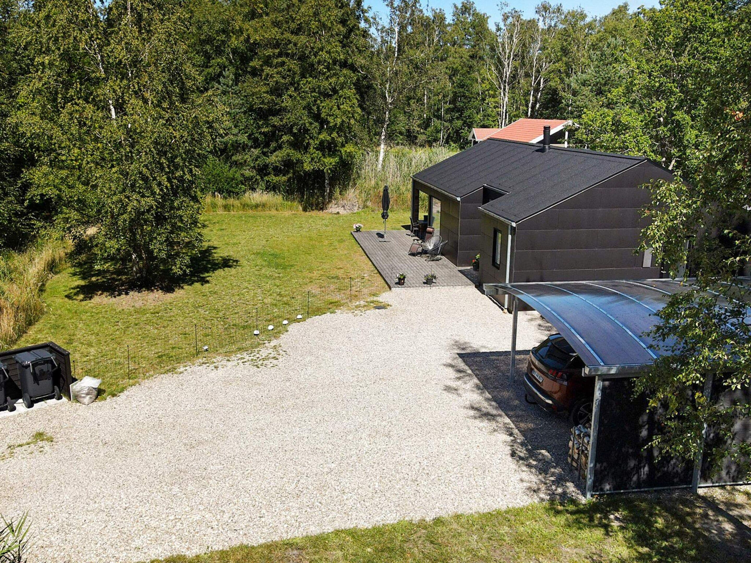 Ein modernes Haus mit einem Schotterweg, der zu einer überdachten Terrasse führt.