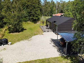 A modern house with a gravel driveway leading to a covered patio area.