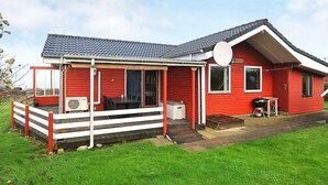 Ein rotes Haus mit überdachter Veranda, Satellitenschüssel und Grill.