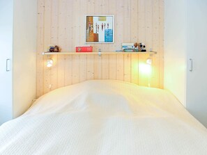 A bedroom with a bed, a wooden wall, a shelf with books and a teddy bear, and a framed picture above the shelf. - Idyllic Holiday Home in Tranekær near Sea (Tranekaer)