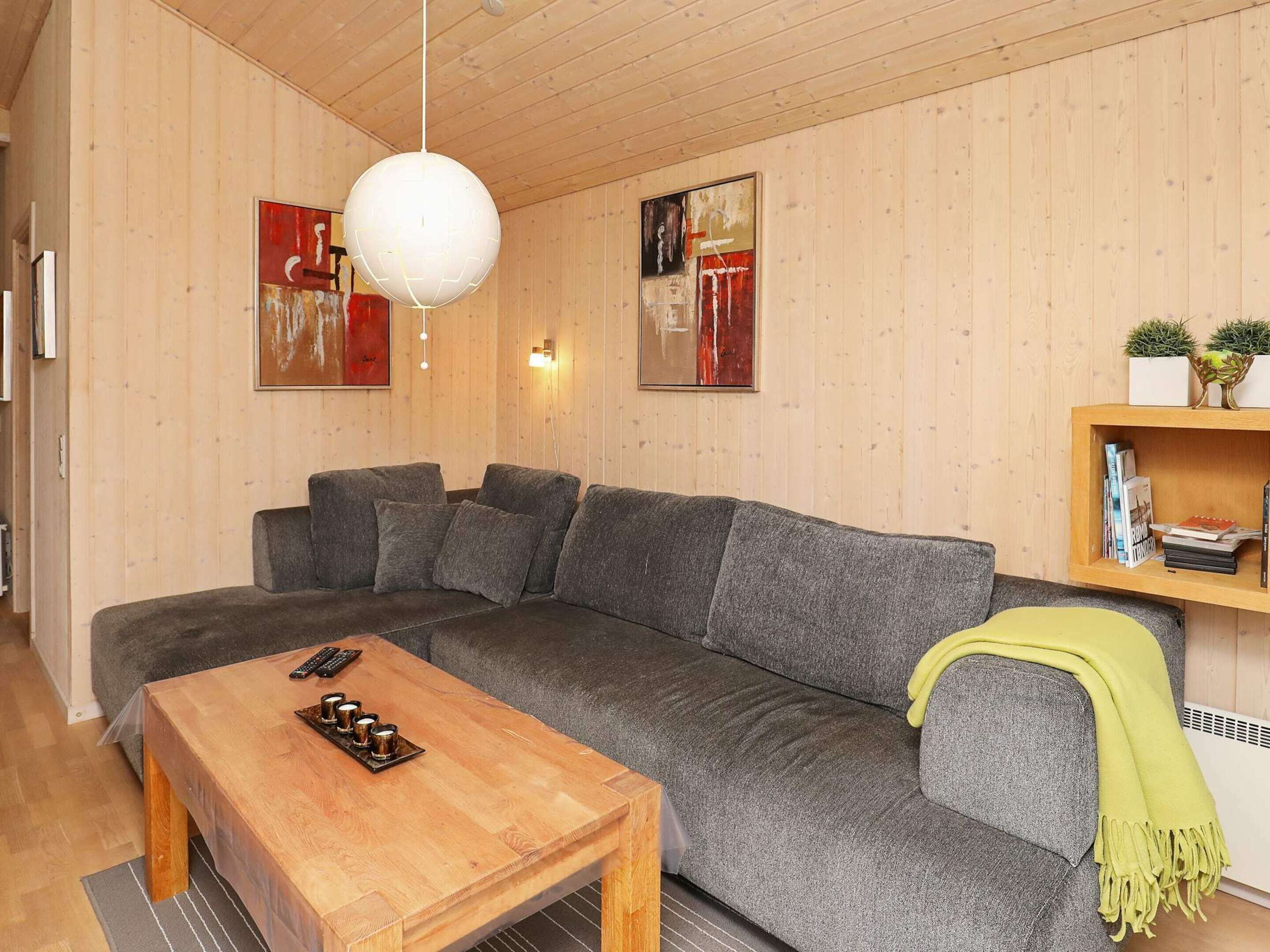 A cozy living room with a grey sofa, a wooden coffee table, and a hanging light fixture.