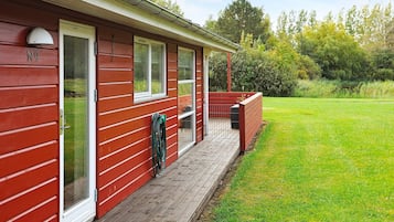 A red building with a covered porch, a grassy yard, and a clear sky.