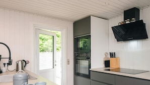 Een moderne keuken met een inbouwoven, een koffiezetapparaat en een messenblok op het aanrecht.