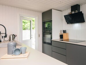 A modern kitchen with a built-in oven, a coffee maker, and a knife block on the countertop.