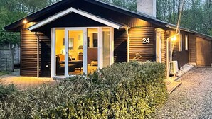 Een moderne blokhut met glazen deuropening, huisnummer 24, en schoorsteen.