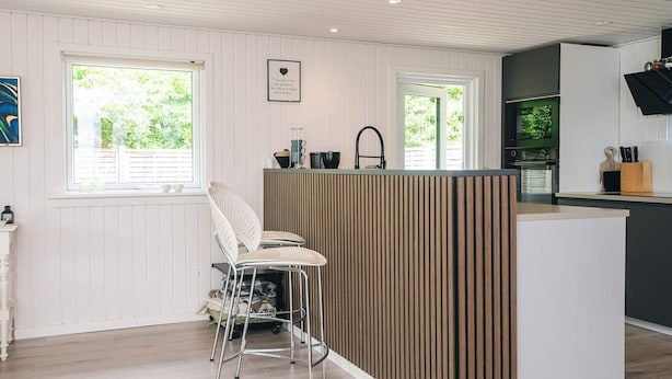 Een moderne keuken met een houten kookeiland, barstoelen en uitzicht op de omgeving.
