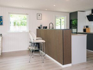 Une cuisine moderne avec un îlot central en bois, des tabourets de bar et une vue sur l’extérieur.