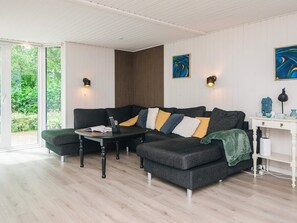 Un salon moderne avec un canapé d’angle, une petite table et une console blanche agrémentée d’objets décoratifs.