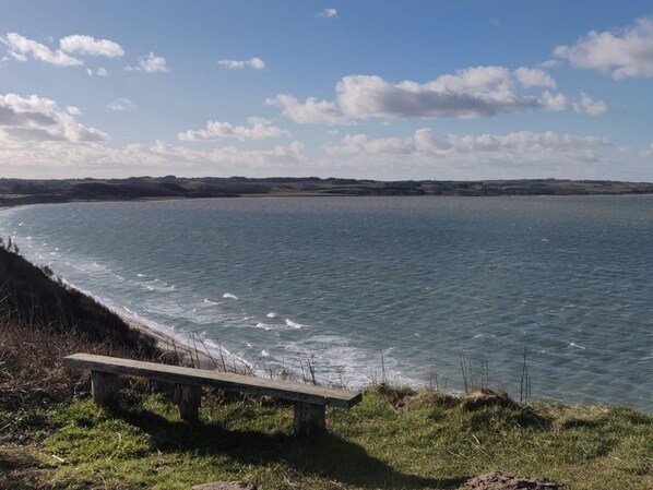 A bench by a calm sea with a clear sky.