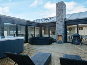 A modern outdoor patio with a hot tub, seating area, and a grill. - Modern Holiday Home in Glesborg With Swimming Pool (Glesborg)