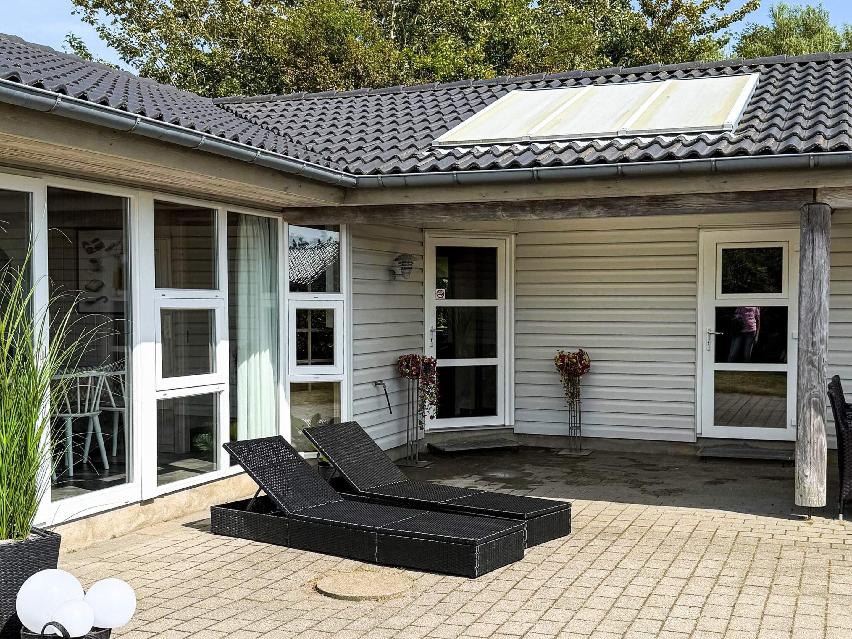 A house with a covered patio area, large windows, and a flat roof with a skylight.