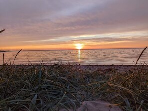 A beach scene with grass in the foreground and a sunset over the water. - 4 Star Holiday Home in Tarm (Tarm)