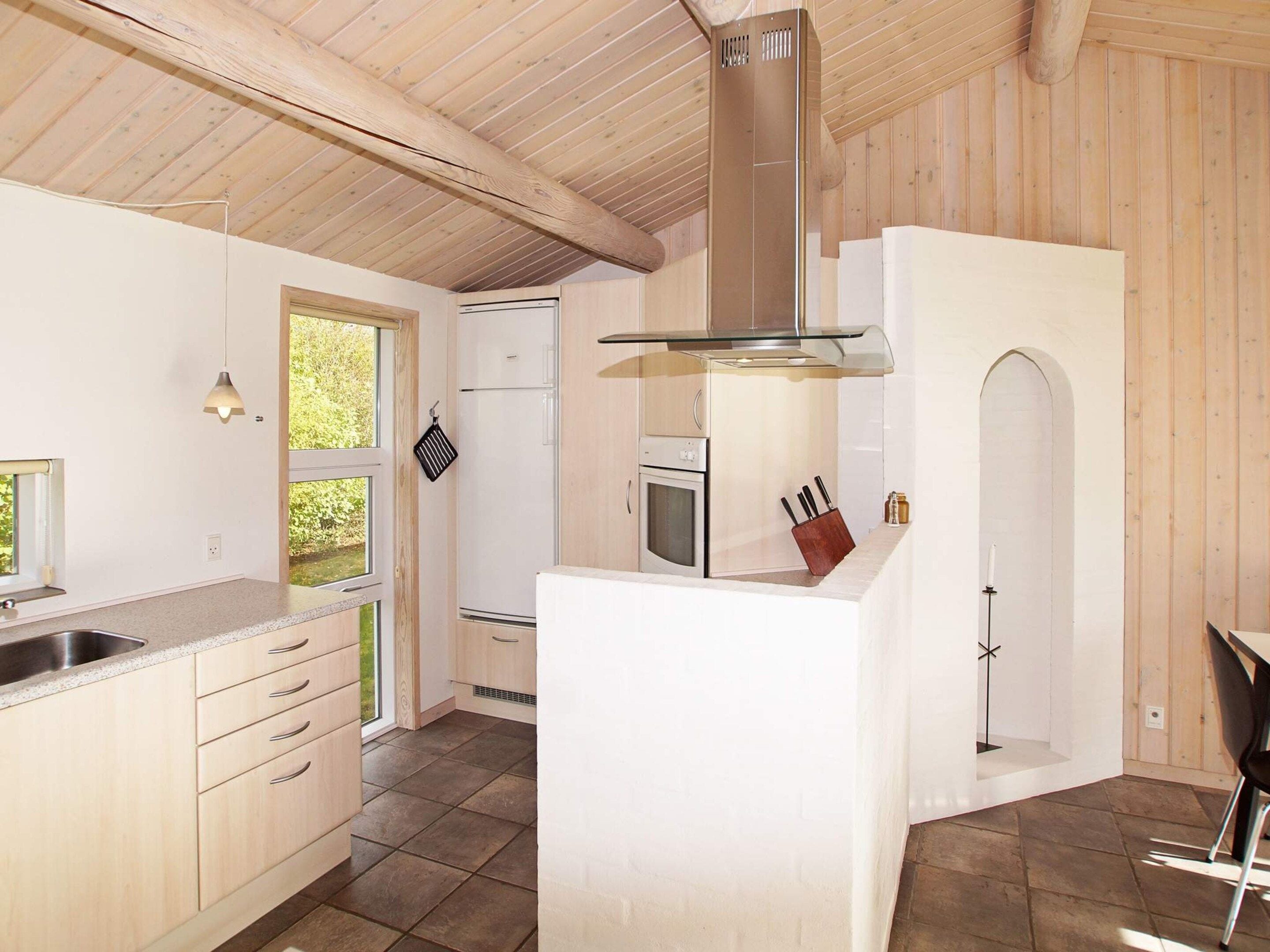 Una cocina moderna con una isla central, armarios de madera y una campana extractora de acero inoxidable.