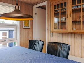 Un espace repas comprenant une table, des chaises, un luminaire suspendu et un lambris en bois.