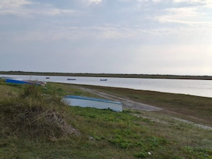 A river with boats, grassy banks, and a cloudy sky.