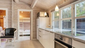 A modern kitchen with a built-in oven, a sink, and a window overlooking a garden.