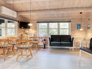 A wooden interior with a sofa, chairs, and a dining table.