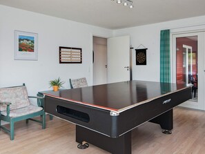 A billiards table in a room with a door, a framed picture, and a dartboard.