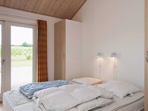 Een slaapkamer met een bed, een raam met gordijnen en uitzicht op de omgeving.