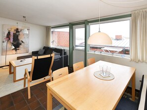A modern living room with a dining area, a large window with curtains, and a painting on the wall. - 4 Star Holiday Home in Henne (Henne)