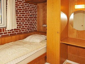 A single bed with a wooden headboard, a brick wall, and a mirror with a round frame. - 4 Star Holiday Home in Henne (Henne)