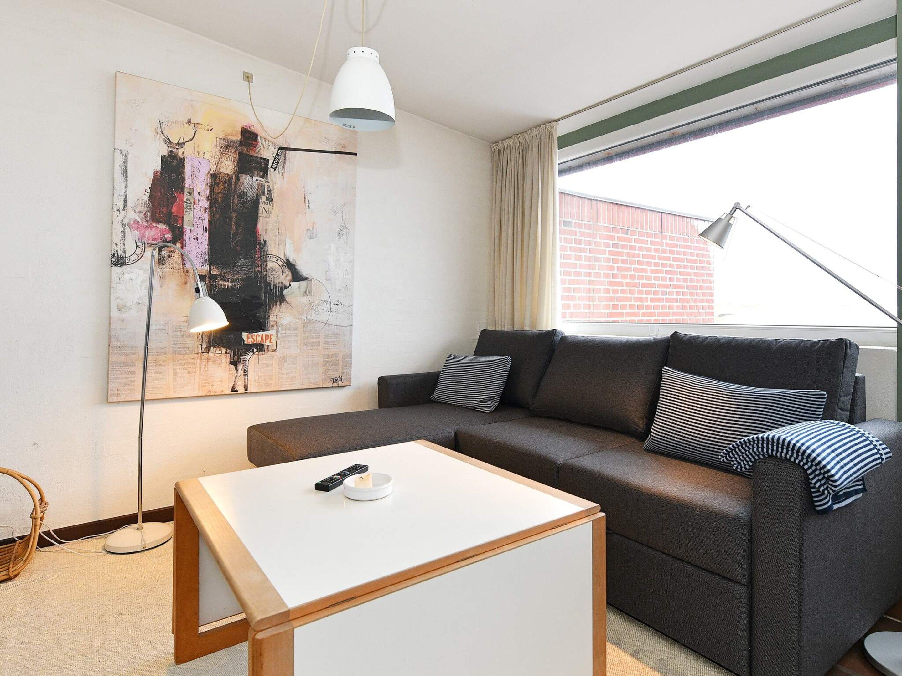Una sala de estar moderna con un sofá, una mesita, una lámpara y un cuadro abstracto grande en la pared.
