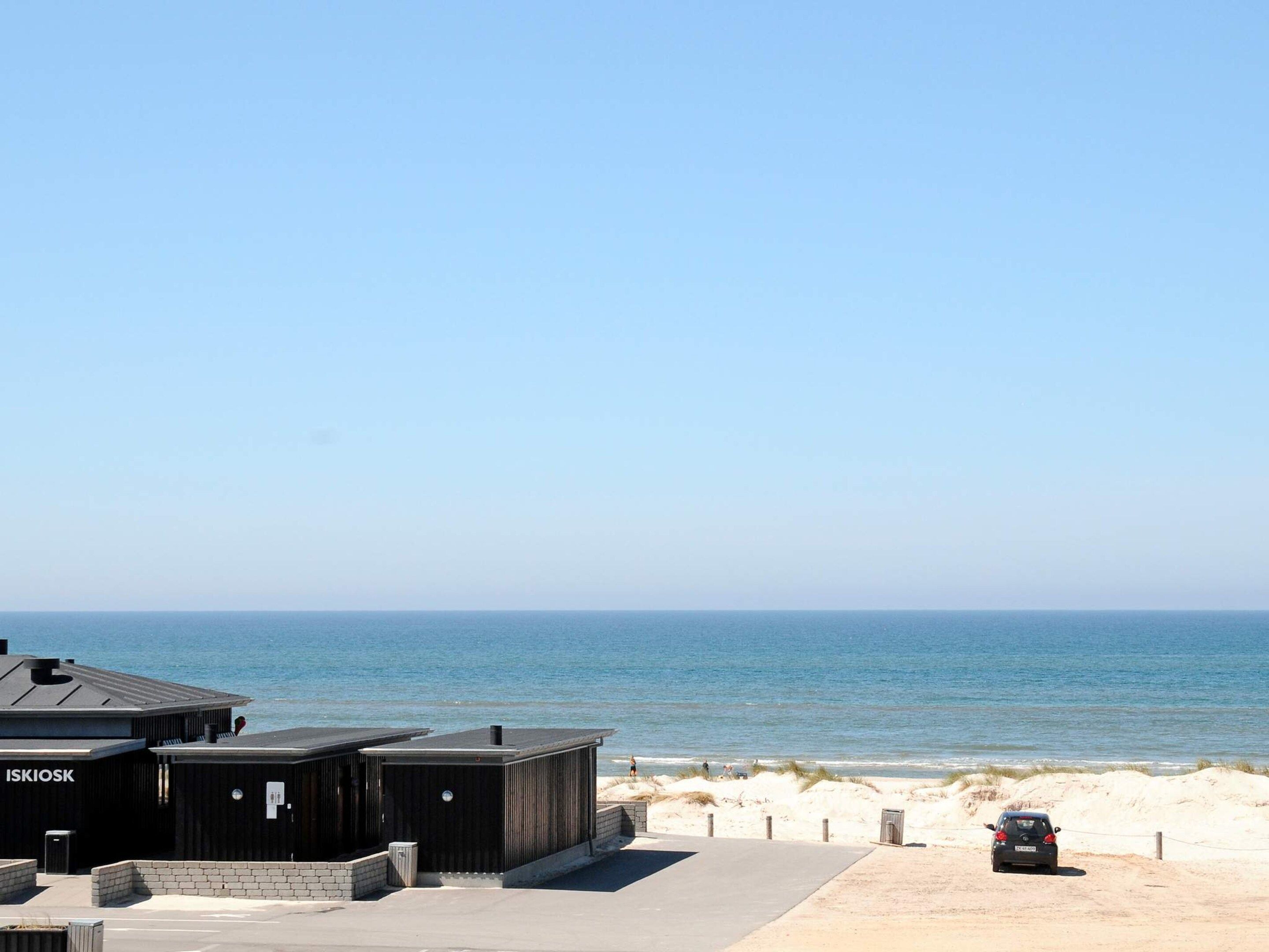 Instalación frente a la playa con zona de estacionamiento y vistas al océano.