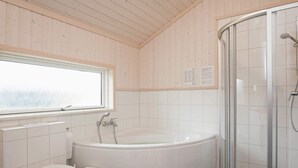 Een moderne badkamer met een vrijstaand bad, een toilet en een douchecabine van glas.