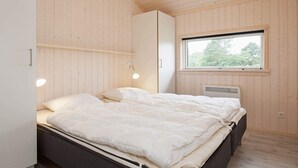 Een slaapkamer met een bed, een kledingkast, een raam en een plafondlamp.