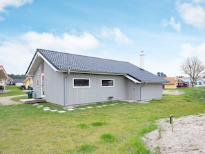 A single-story building with a sloped roof, a chimney, and a small porch with steps leading to the entrance. - Holiday Home in Großenbrode (Grossenbrode)