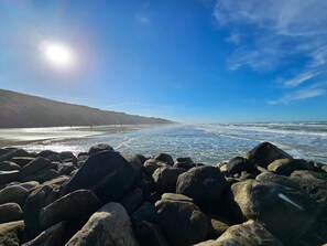 A rocky beach with waves, a clear sky, and distant mountains. - 5 Star Holiday Home in Lokken (Lokken)