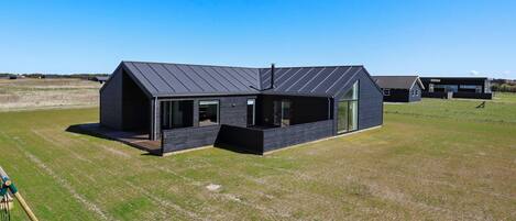 A modern house with a large open porch, a garage, and a spacious yard.