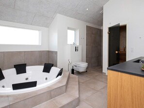 A modern bathroom with a freestanding bathtub, a toilet, and a sink. - 5 Star Holiday Home in Lokken (Lokken)