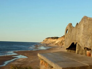 A beach with a stone structure in the foreground, a clear sky, and a distant cliff. - 5 Star Holiday Home in Lokken (Lokken)