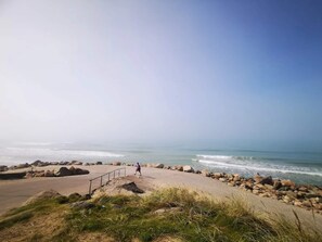 A coastal pathway with a railing, leading to the sea.