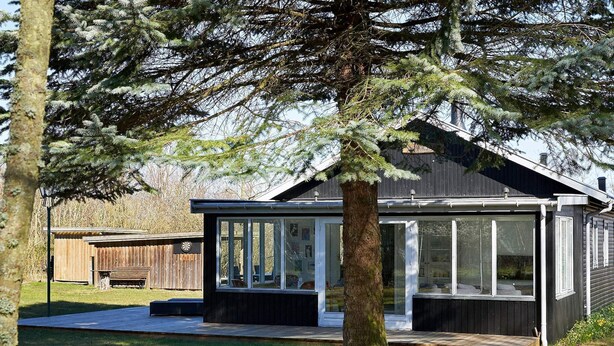 A modern house with a large glass window, a wooden deck, and a tree in the foreground. - 6 Person Holiday Home in Hasle-by Traum (Hasle)