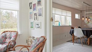 A room with wicker chairs, a dining table with chairs, and a wall with framed pictures. - 6 Person Holiday Home in Hasle-by Traum (Hasle)