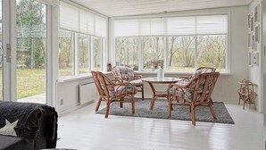 A bright room with large windows, wicker furniture, and a white ceiling. - 6 Person Holiday Home in Hasle-by Traum (Hasle)