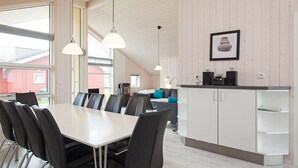 A modern kitchen with white cabinets, a black countertop, and a hanging light fixture. - Holiday Home in Großenbrode (Grossenbrode)