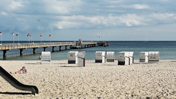 A beach with a pier, beach chairs, and a slide. - Holiday Home in Großenbrode (Grossenbrode)