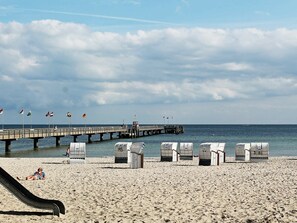 A beach with a pier, beach chairs, and a slide. - Holiday Home in Großenbrode (Grossenbrode)