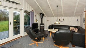 A cozy living room with a fireplace, leather sofas, a TV, and a dining table. - 8 Person Holiday Home in Oksbol-by Traum (Oksbol)
