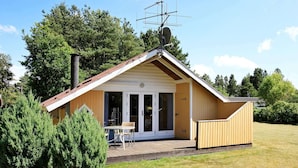 A small wooden cabin with a sloped roof, a patio with a table and chairs, and a satellite dish. - 8 Person Holiday Home in Oksbol-by Traum (Oksbol)