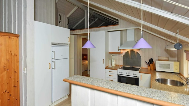 A compact kitchen with a built-in oven, a microwave, and a sink. There are two pendant lights hanging above the counter. - 8 Person Holiday Home in Oksbol-by Traum (Oksbol)