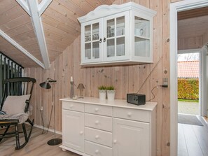 A wooden interior with a white cabinet, a rocking chair, and a small radio.